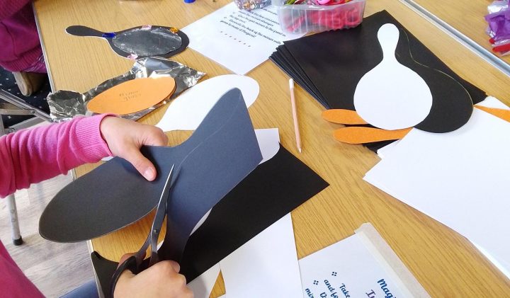 Creating penguin crafts from black paper at the Eric Morecambe Centre.