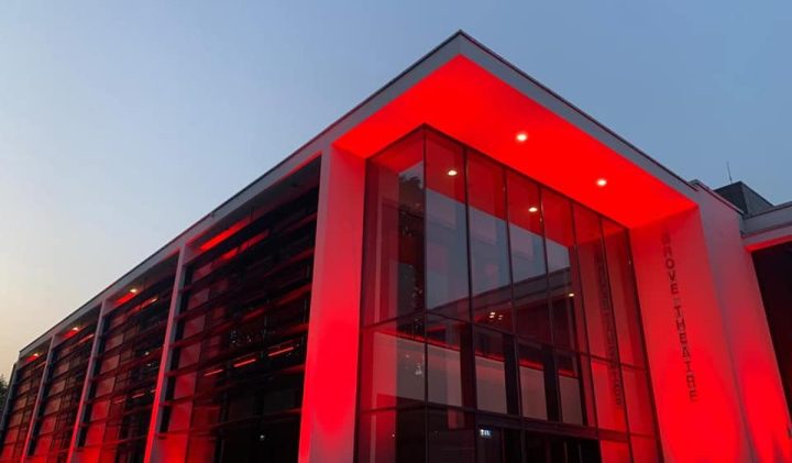 Modern Dunstable building with large glass windows lit in red at dusk.
