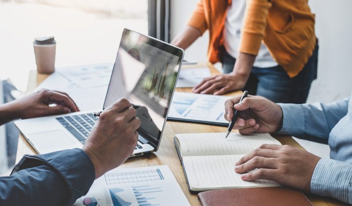 Team working with laptop and notepad at a desk, reviewing charts for the upcoming shows.