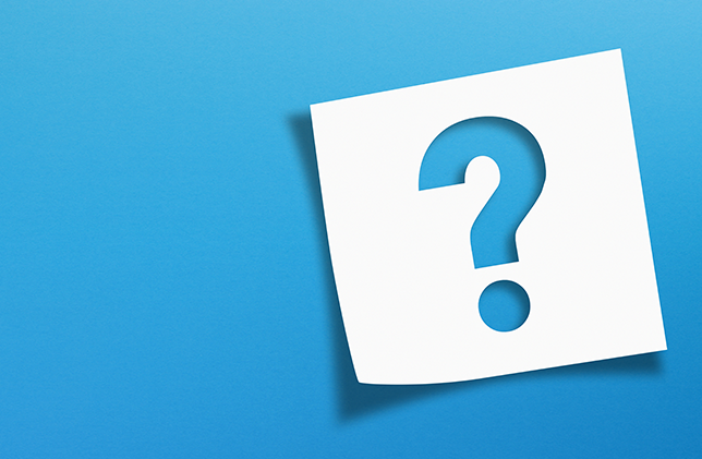 A white sticky note with a cut-out question mark in the centre is placed on a bright blue background. The question mark creates a visual contrast by revealing the blue colour through the cut-out.