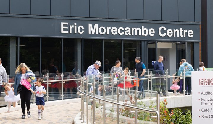 Children in costumes gather outside the Eric Morecambe Centre by the car park.